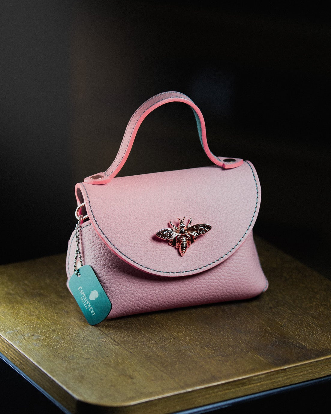 Pink micro handbag with a decorative emblem 