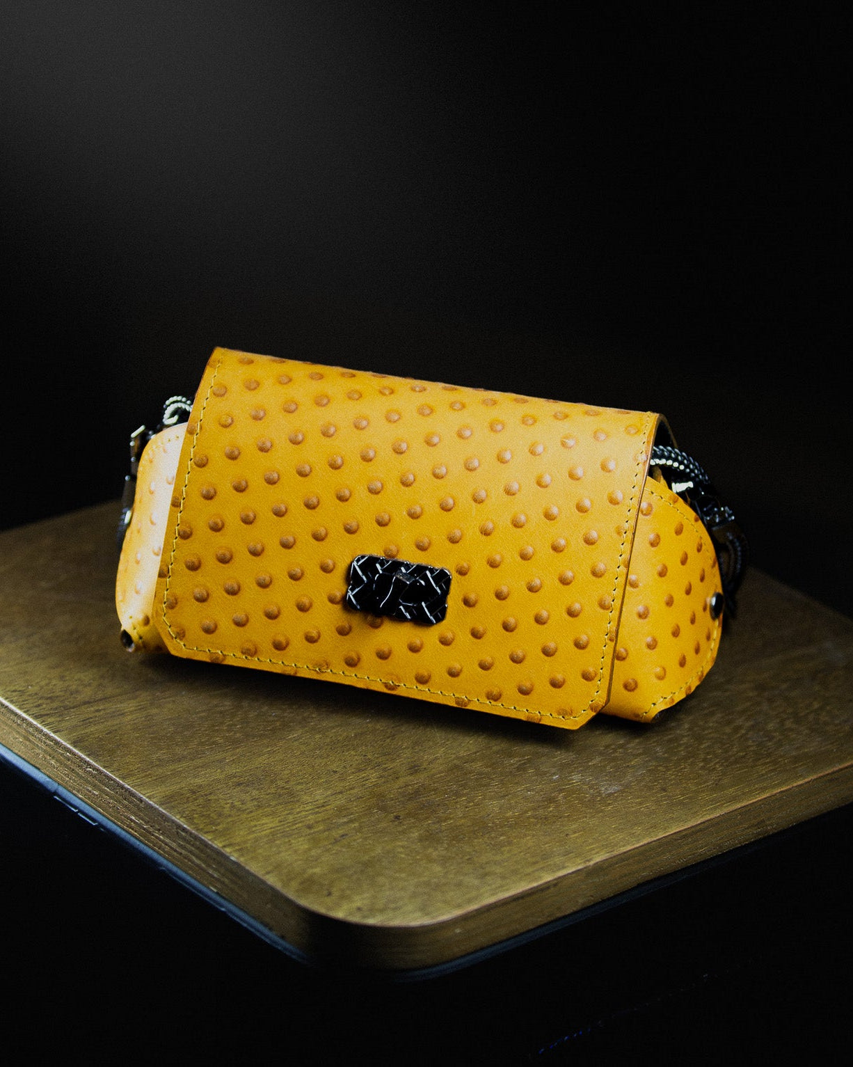 medium leather bag on a wooden surface on a dark background