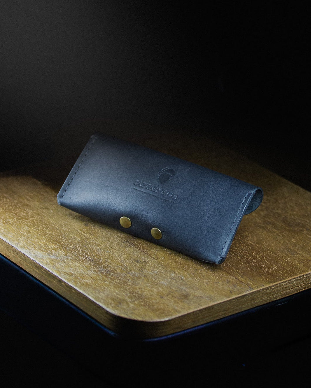 Blue leather wallet on a wooden surface with a dark background