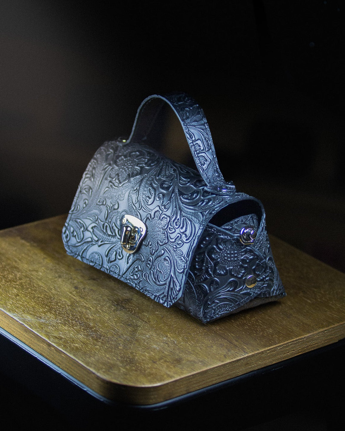 medium leather bag on a wooden surface on a dark background