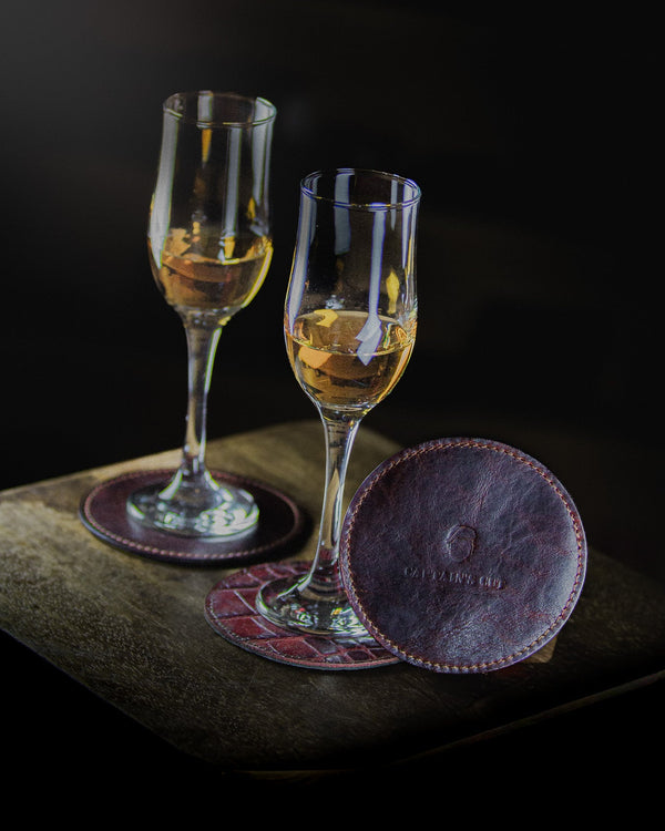 two glasses of wine on coasters standing on a wooden surface on a black backgroung