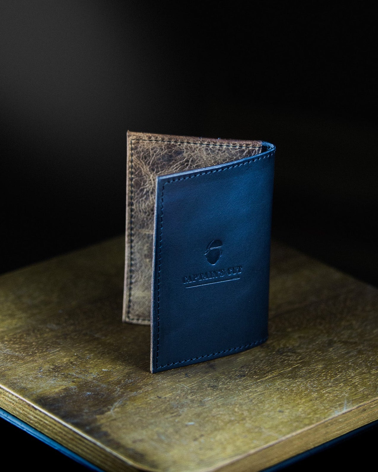 Blue leather wallet on a textured surface with a dark background