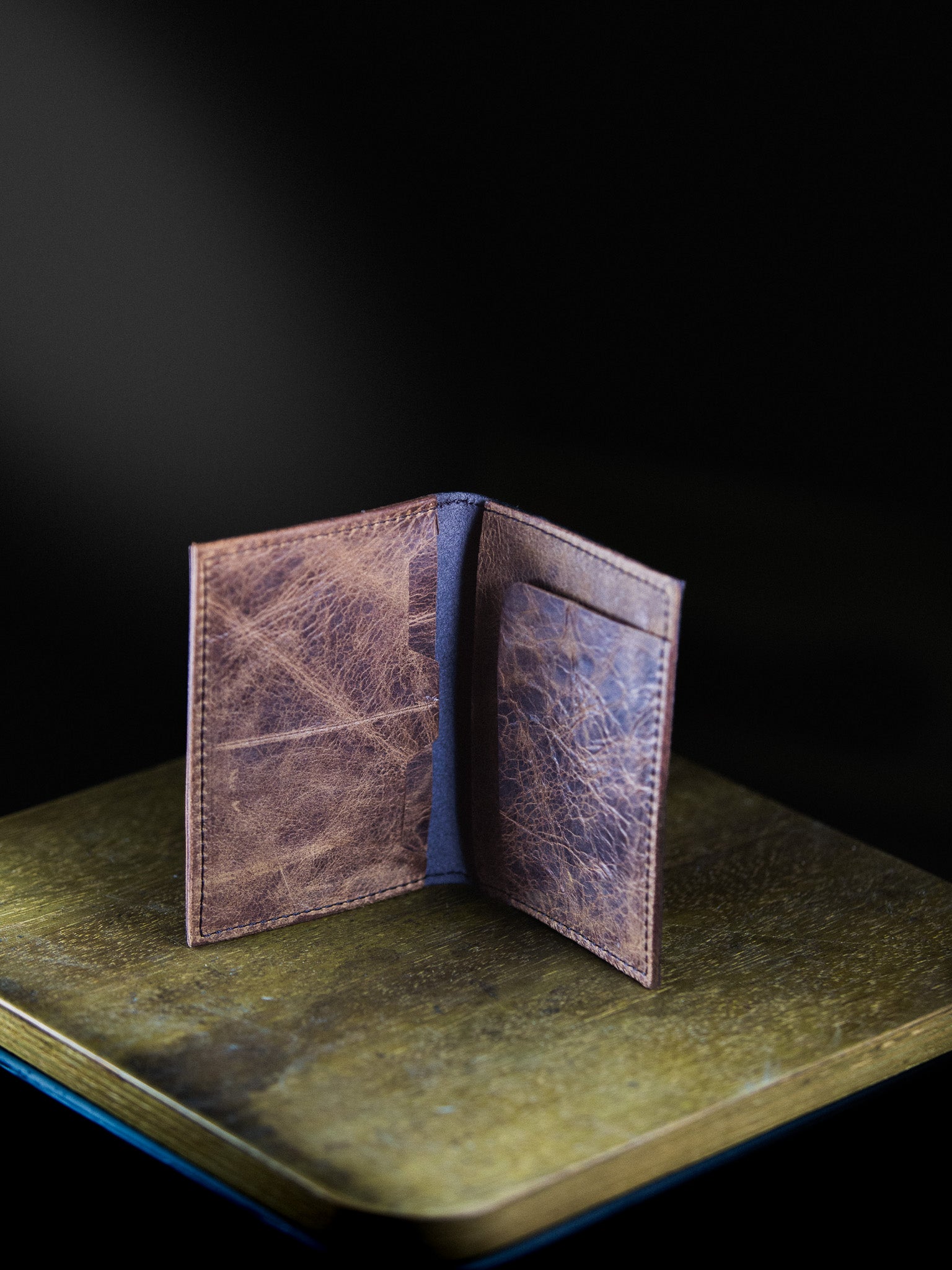 Brown leather wallet with blue interior on a dark surface