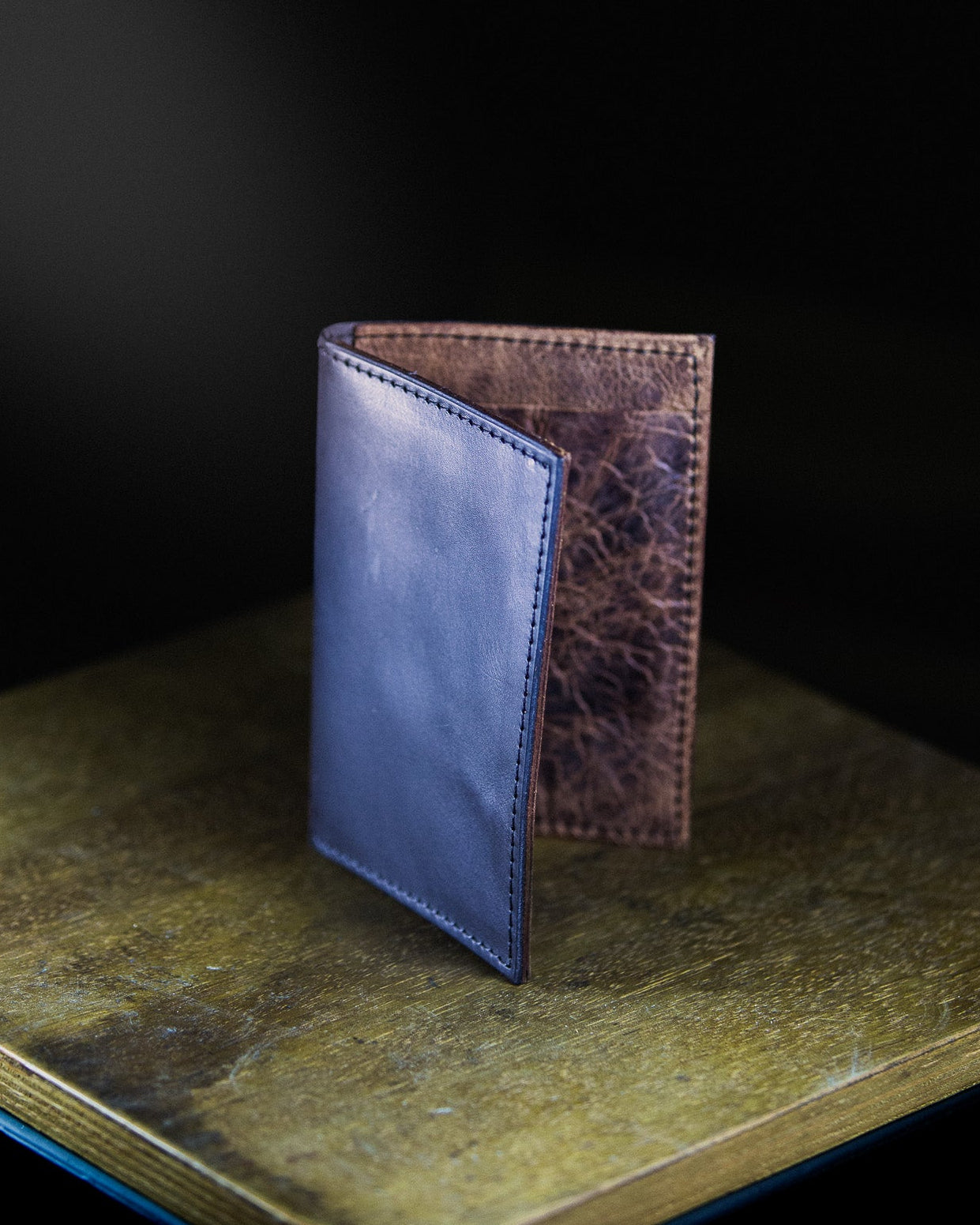 Two leather wallets on a textured surface with a dark background