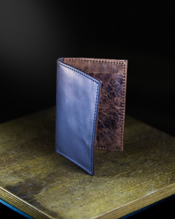 Two leather wallets on a textured surface with a dark background