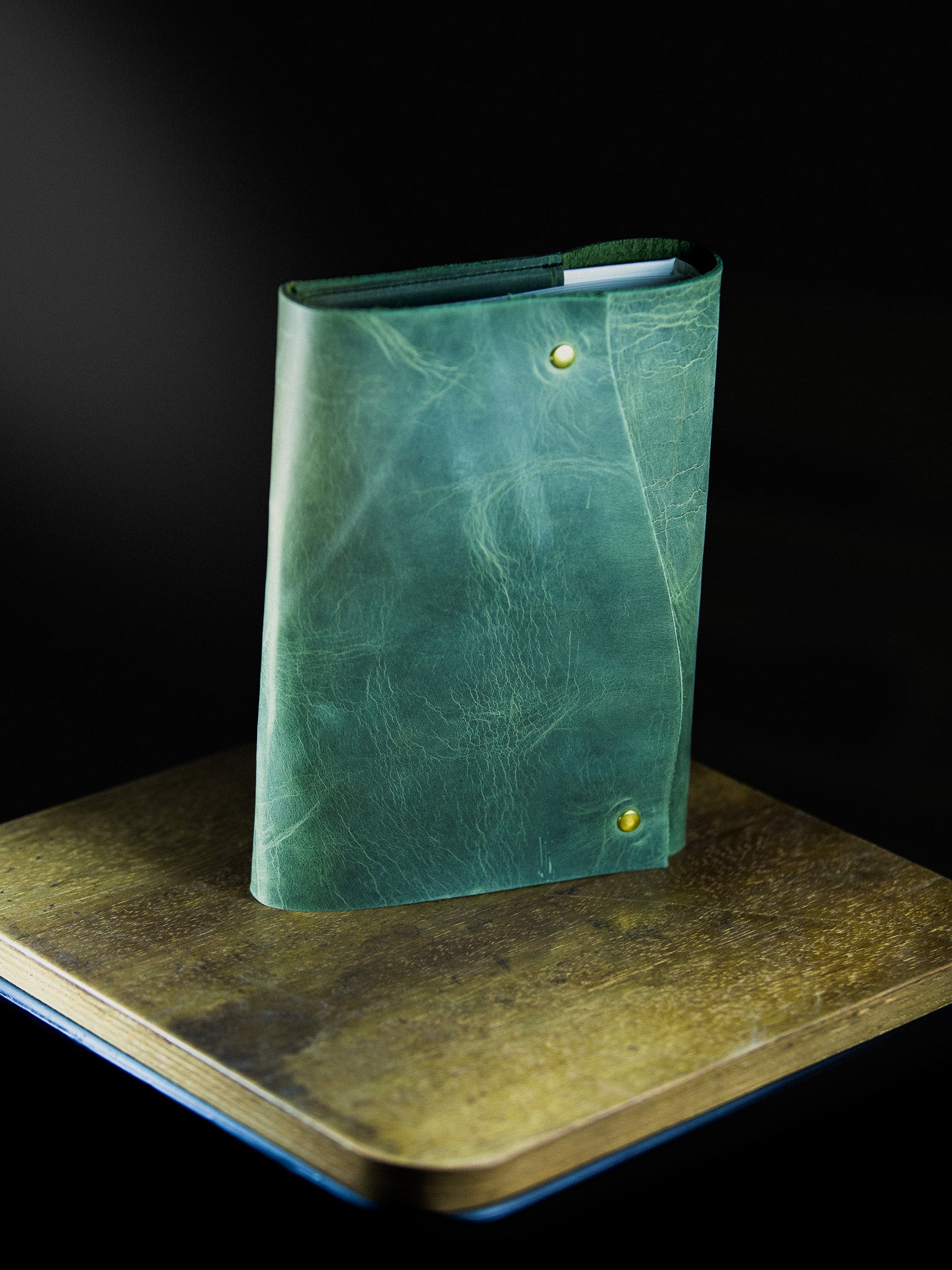 Green leather wallet on a dark surface with a black background