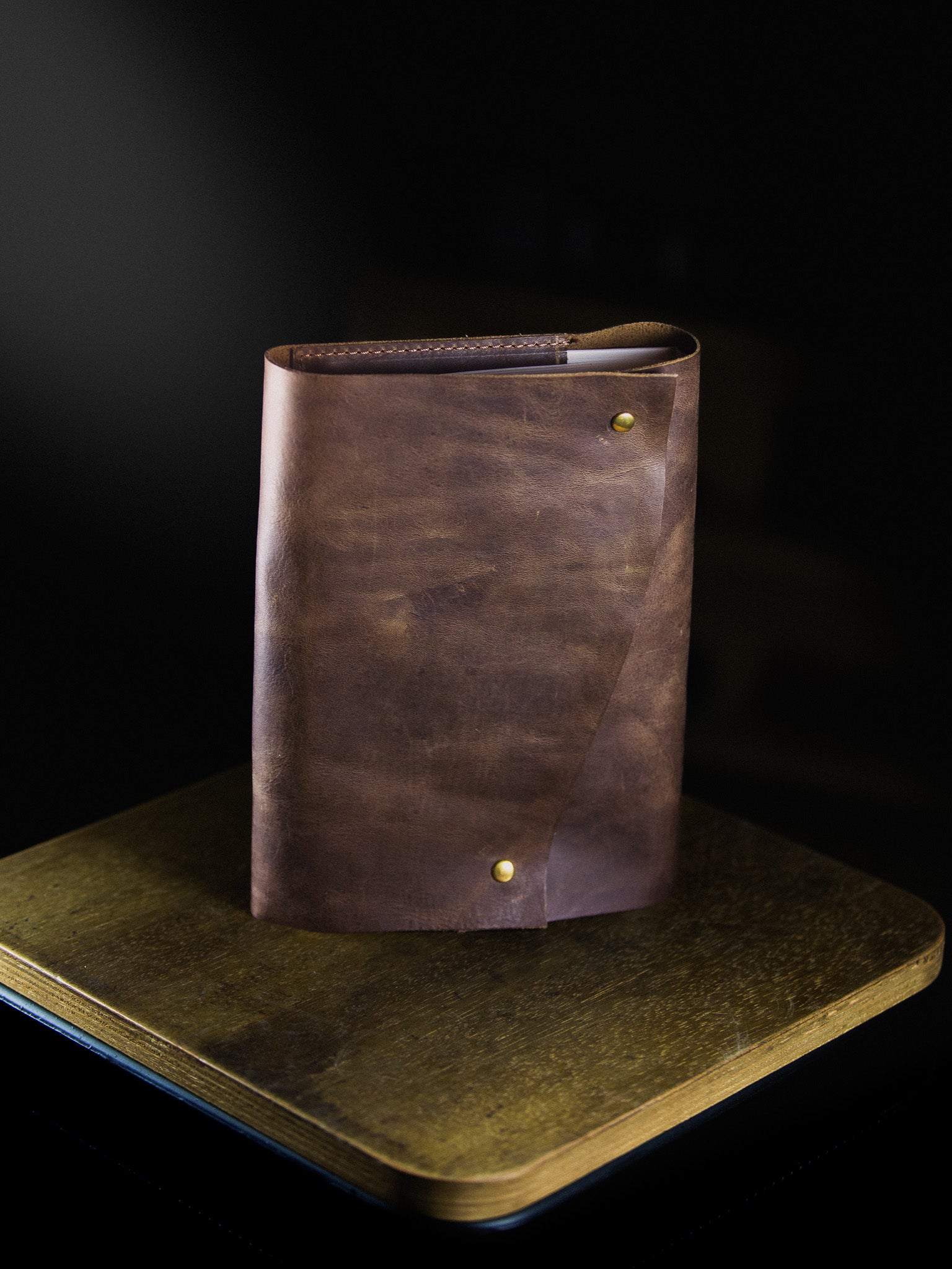 Brown leather notebook on a dark surface with a black background