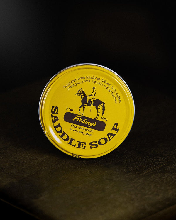 Yellow container of Saddle Soap on a dark leather surface