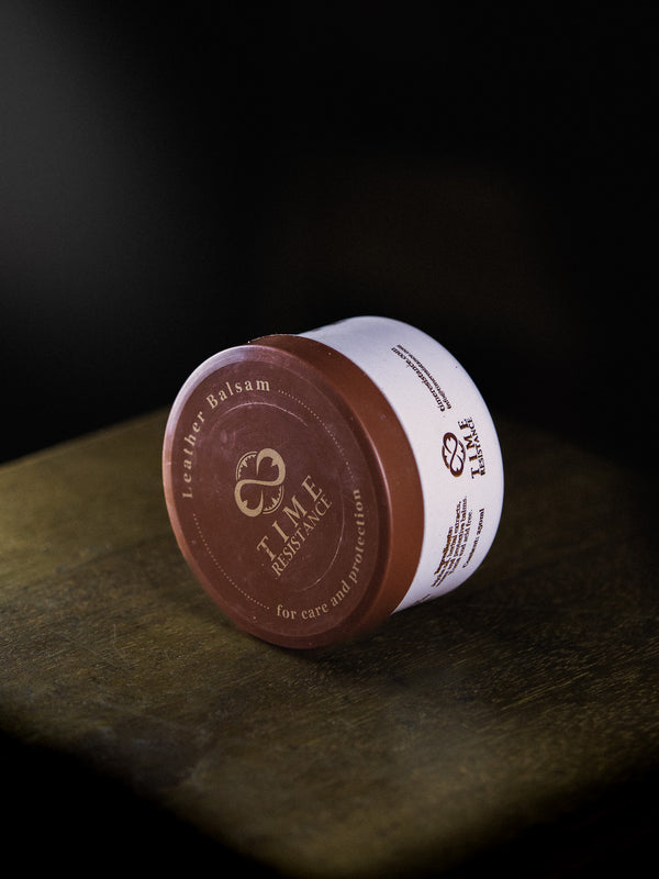 packing of leather care balm on a wooden surface on a dark background