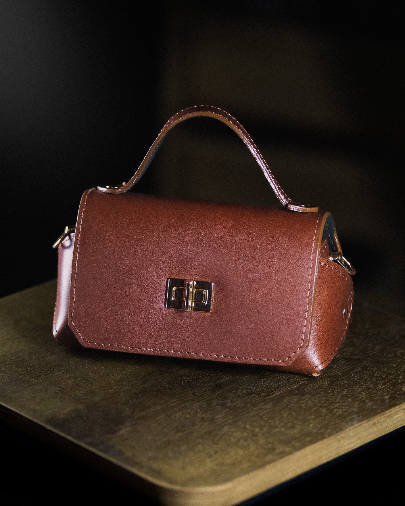 medium leather bag on a wooden surface on a dark background