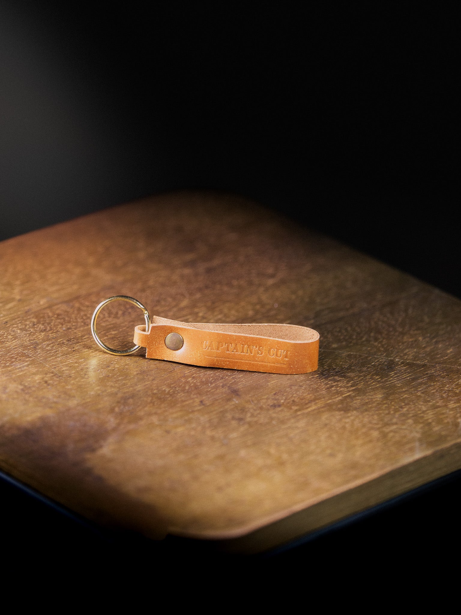 Brown leather keychain with a metal ring on a dark surface