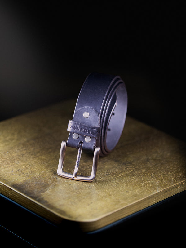 black leather belt with silver buckle on a textured surface