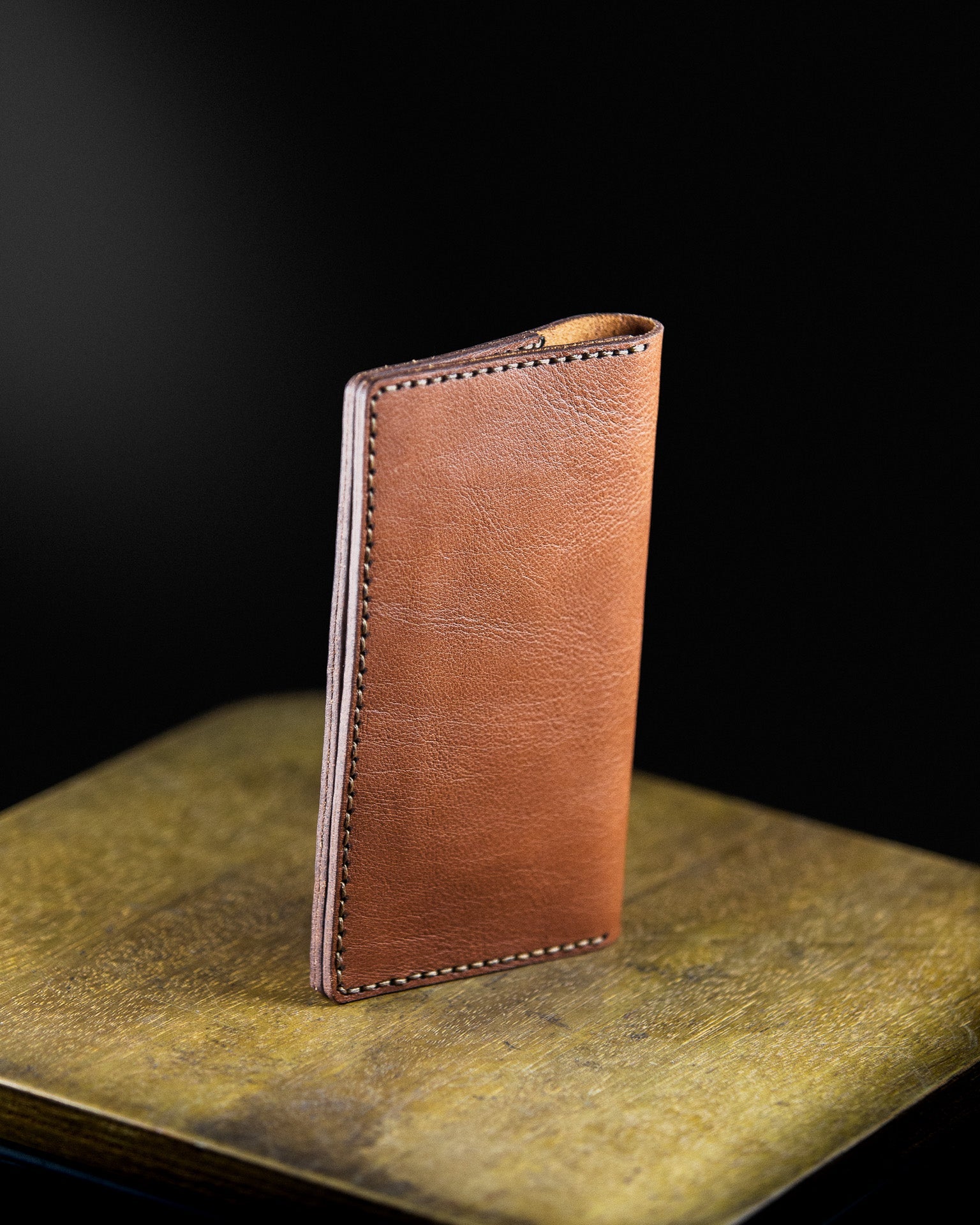 brown leather tobacco pouch on a wooden sourface on a dark background