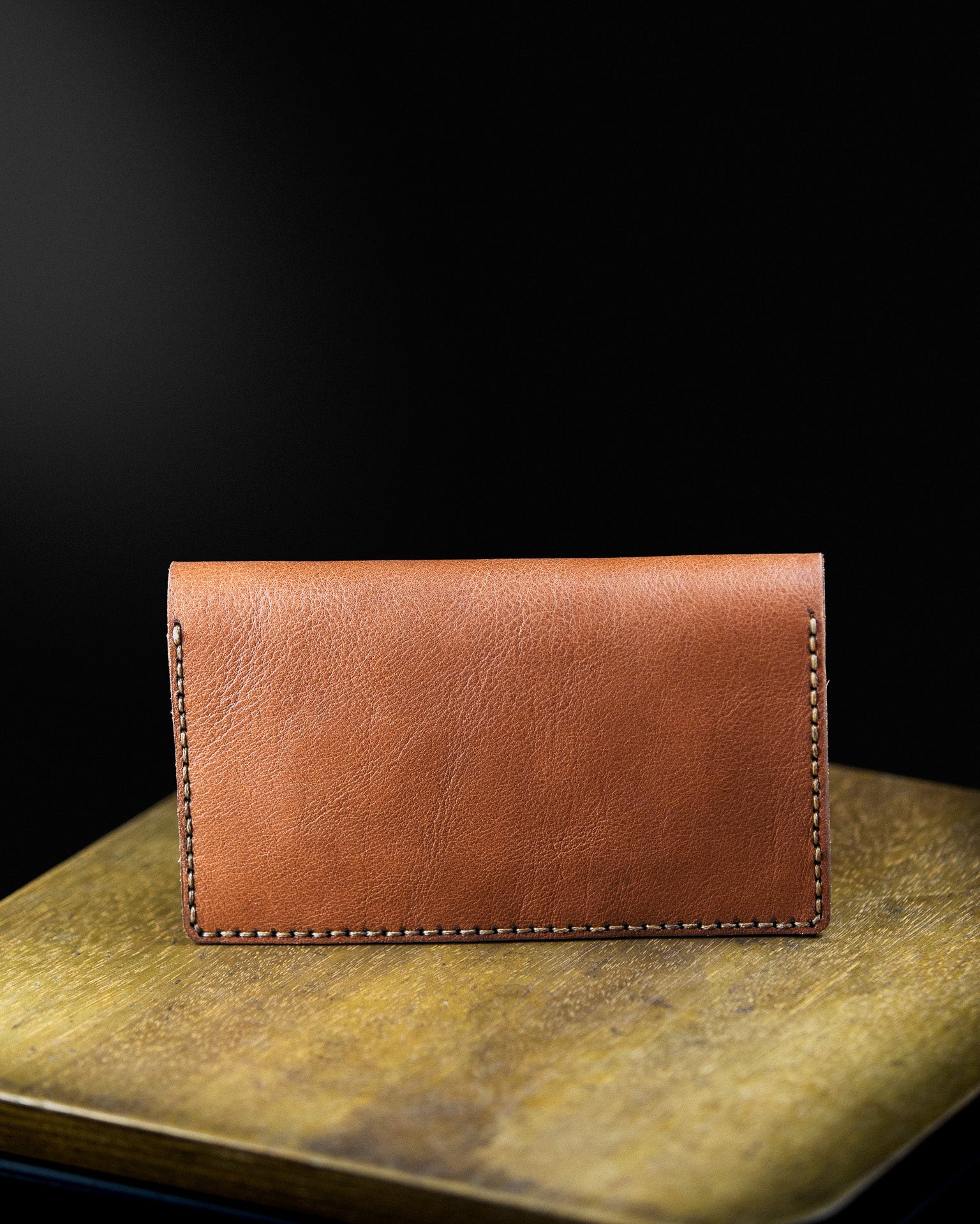 brown leather tobacco pouch on a wooden sourface on a dark background - laying
