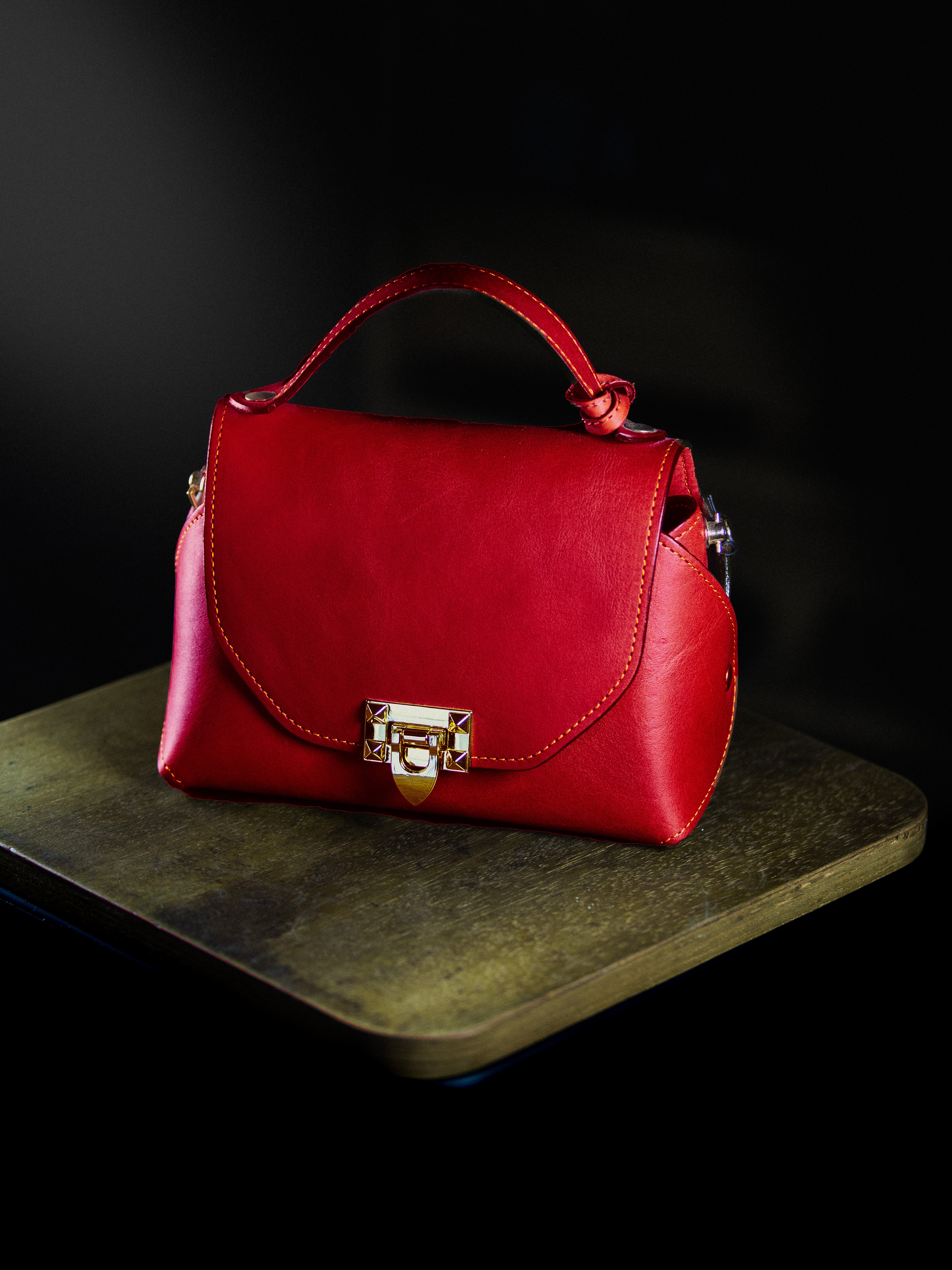 Redleather handbag with a gold lock on a dark surface